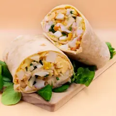 Pyszna tortilla z jajkiem, warzywami i kurczakiem, podana na desce z zieloną sałatą. Idealna na szybki lunch.