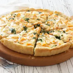 Pyszna tarta z łososiem, szpinakiem i serem feta, pokrojona na kawałki, na drewnianej desce.