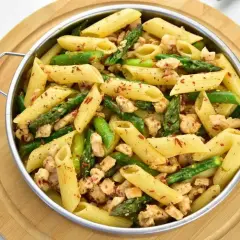 Penne z kurczakiem i szparagami, posypane papryką. Pyszne danie, które zachwyci każdego.