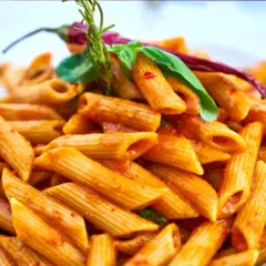 Penne w pikantnym sosie pomidorowym, ozdobione papryczką chili i bazylią. Danie wygląda jak makaron Gigi Hadid, idealne na szybki lunch.