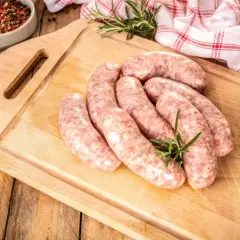 Surowa biała kiełbasa na desce, gotowa do przygotowania. Zioła i przyprawy dodają apetycznego wyglądu.